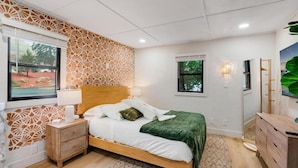 Un dormitorio con cama, mesita de noche, lámpara y ventana con vistas.