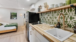 Una cocina compacta con un lavamanos blanco, una estufa negra y una encimera de madera.