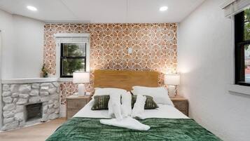 Habitación de hotel con cama, mesita de noche, lámpara, chimenea y pared con diseño.