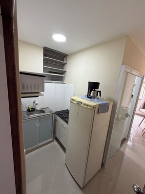 Eine kleine Küche mit Kühlschrank, Herd und Spüle.