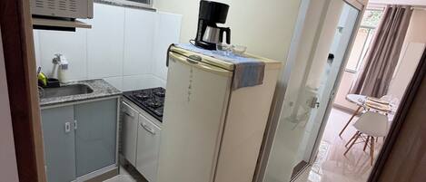 A compact kitchen with a refrigerator, stove, and coffee maker.
