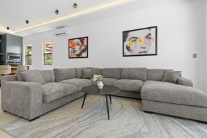 A modern living room with a grey sectional sofa, a round coffee table, and two framed artworks on the wall. - Modern Private Pool Villa near Playas del Coco & Playa Hermosa (Coco)