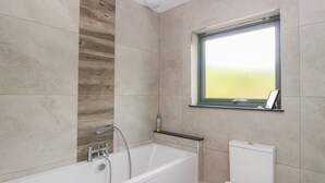 A modern bathroom with a bathtub, toilet, and a window. - Taigh Creag Thulach (Taynuilt)