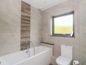 A modern bathroom with a bathtub, toilet, and a window. - Taigh Creag Thulach (Taynuilt)