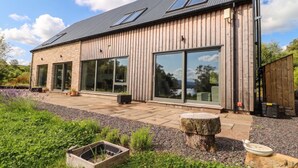 A modern house with large windows, a stone facade, and a well-maintained garden. - Taigh Creag Thulach (Taynuilt)