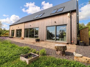 A modern house with large windows, a stone facade, and a well-maintained garden. - Taigh Creag Thulach (Taynuilt)