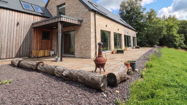 A modern house with a stone facade, large windows, and a covered patio area. - Taigh Creag Thulach (Taynuilt)