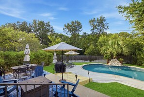 Un jardin avec une piscine, des meubles de patio et une terrasse en bois.