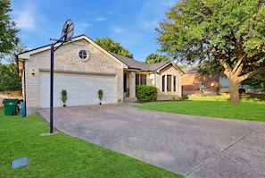 A two-story house with a garage, a small attached structure, and a well-maintained lawn.