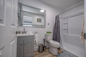 Een badkamer met toilet, wastafel, spiegel en douchegordijn.