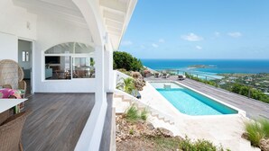 Eine moderne Villa mit Schwimmbad, Sitzgelegenheiten im Freien und Blick auf den Ozean.