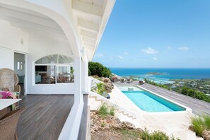 Eine moderne Villa mit Schwimmbad, Sitzgelegenheiten im Freien und Blick auf den Ozean.