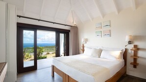 Ein Schlafzimmer mit einem großen Bett, Meerblick und einer Schiebetür.