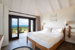 Ein Schlafzimmer mit einem großen Bett, Meerblick und einer Schiebetür.