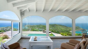 Ein geräumiger Raum mit großem Fenster und Blick auf einen Pool sowie eine reizvolle Küstenlandschaft.