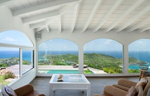 Ein geräumiger Raum mit großem Fenster und Blick auf einen Pool sowie eine reizvolle Küstenlandschaft.