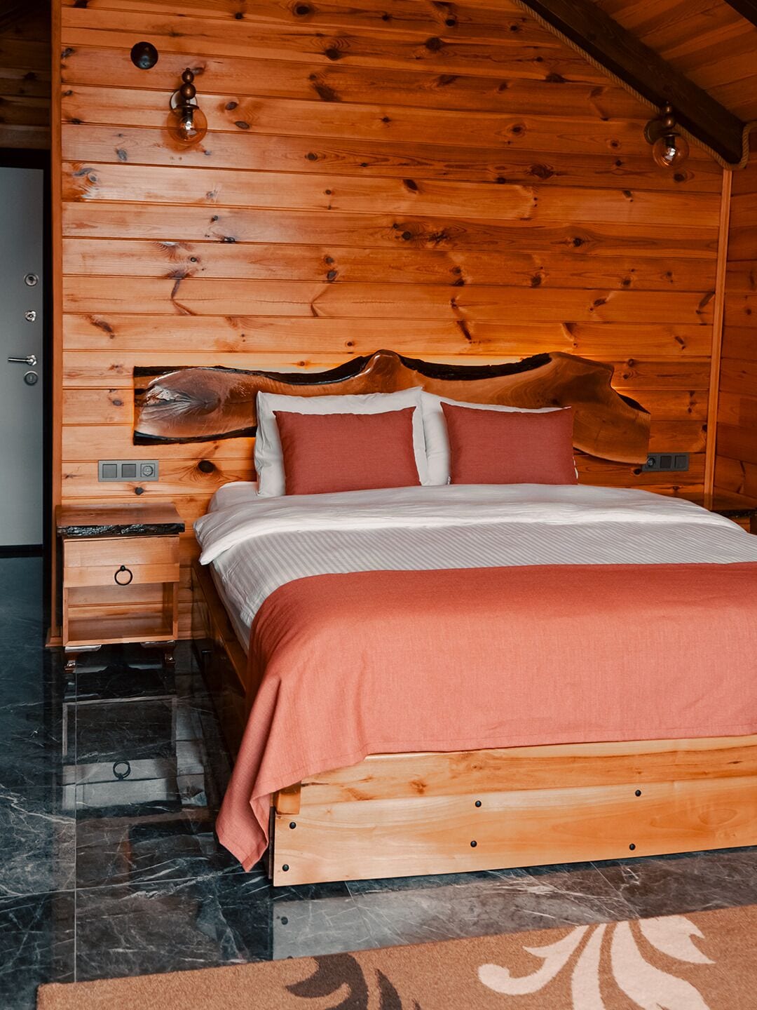 A wooden bed with a headboard, a nightstand, and a marble floor.