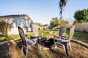 A backyard with a fire pit, outdoor chairs, and a wooden fence.