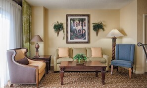 A living room with a sofa, armchair, coffee table, and two lamps. There are two potted plants on the wall and a framed picture above the sofa. - Orlando | Pool & Disney Access | 2BR Suite (Lake Buena Vista)