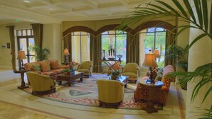 A spacious lobby with a sofa set, armchairs, and a coffee table. There are potted plants and lamps. - Orlando | Pool & Disney Access | 2BR Suite (Lake Buena Vista)