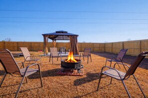 An outdoor patio with a fire pit, seating, and a covered area.