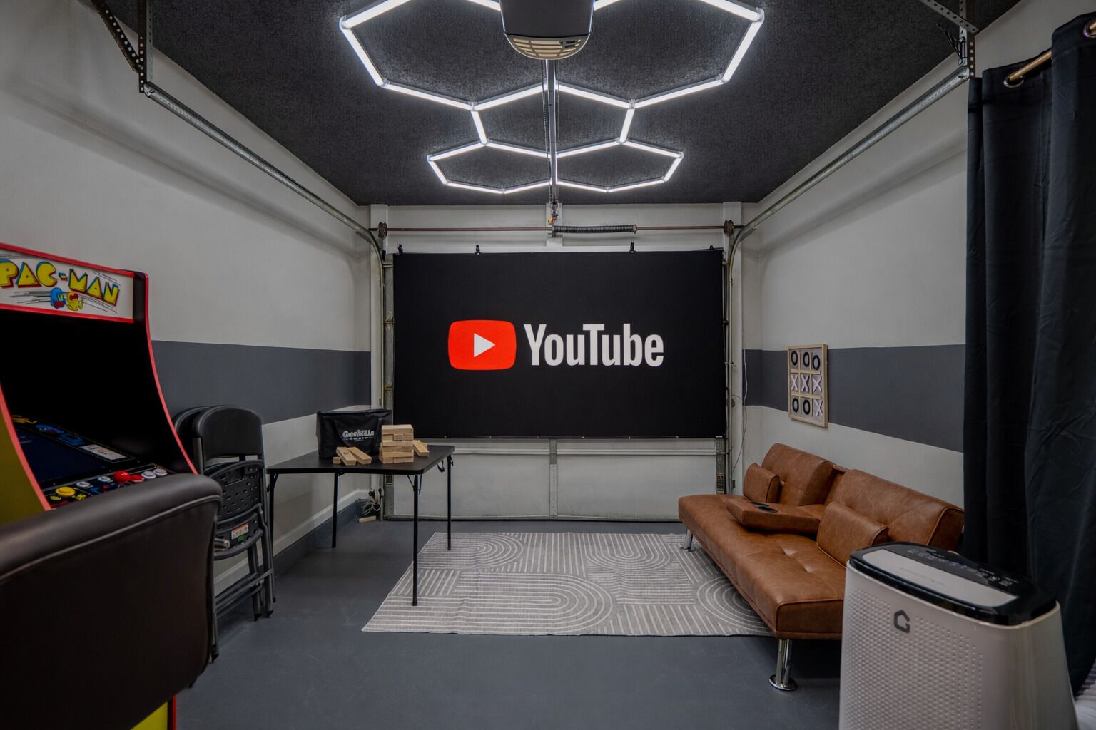 Een kamer met een YouTube-logo op de muur, een gameconsole, een bruine leren bank en een speaker.