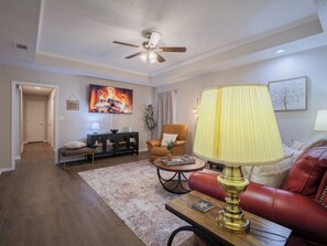 A living room with a ceiling fan, a fireplace, a sofa, a coffee table, and a lamp. - Movie Theater, Arcade, Fire Pit, Cabana, Minutes from Freedom Park (Valdosta)