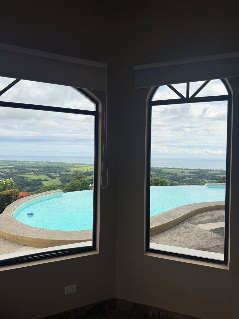 Habitació amb dues finestres que donen a una piscina i un paisatge.