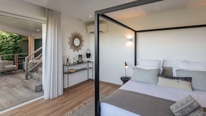 Un dormitorio moderno con cama, mesita de noche y vistas a un balcón con plantas.