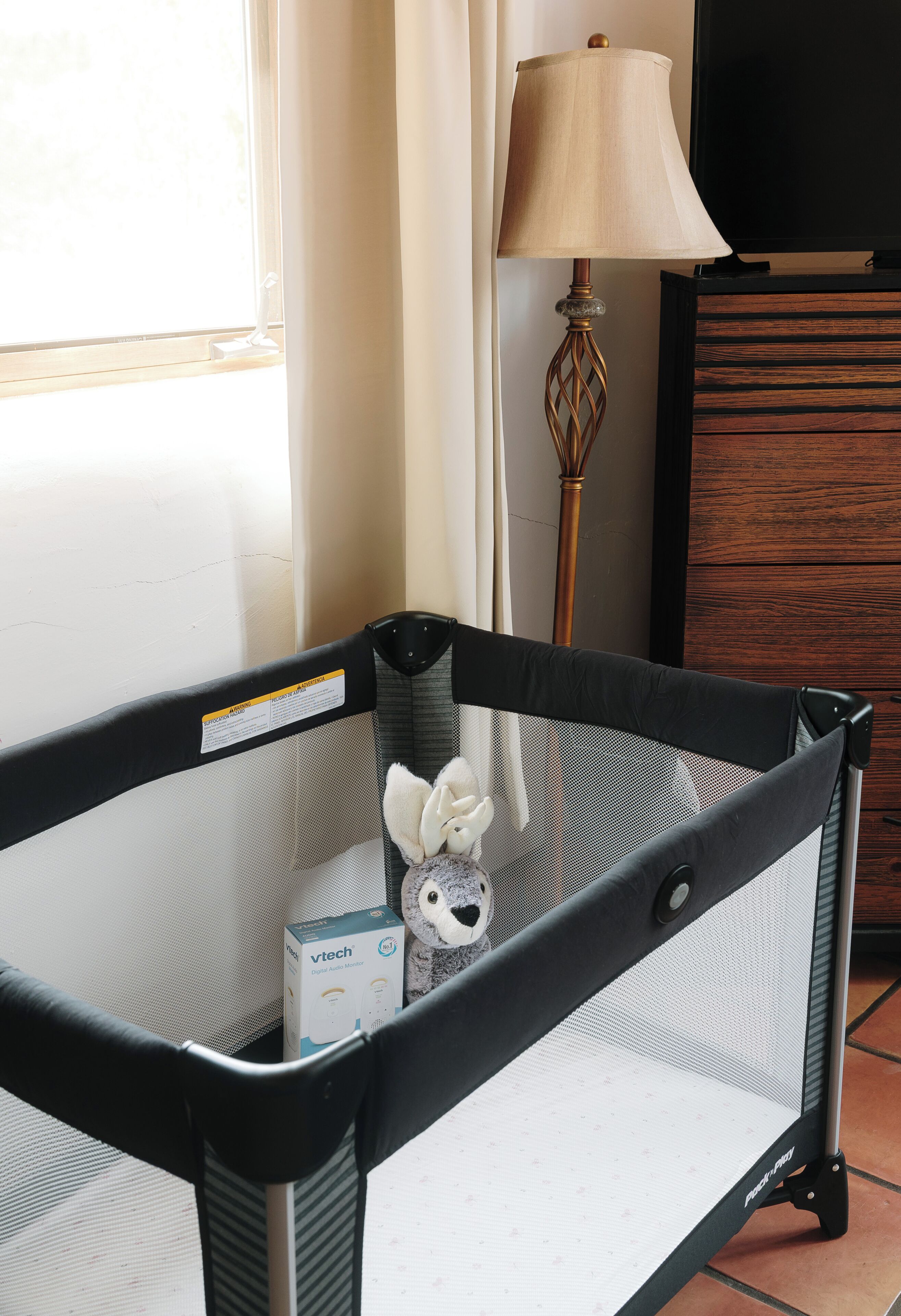 Un corralito para bebés con un monitor de audio digital y un peluche en su interior.