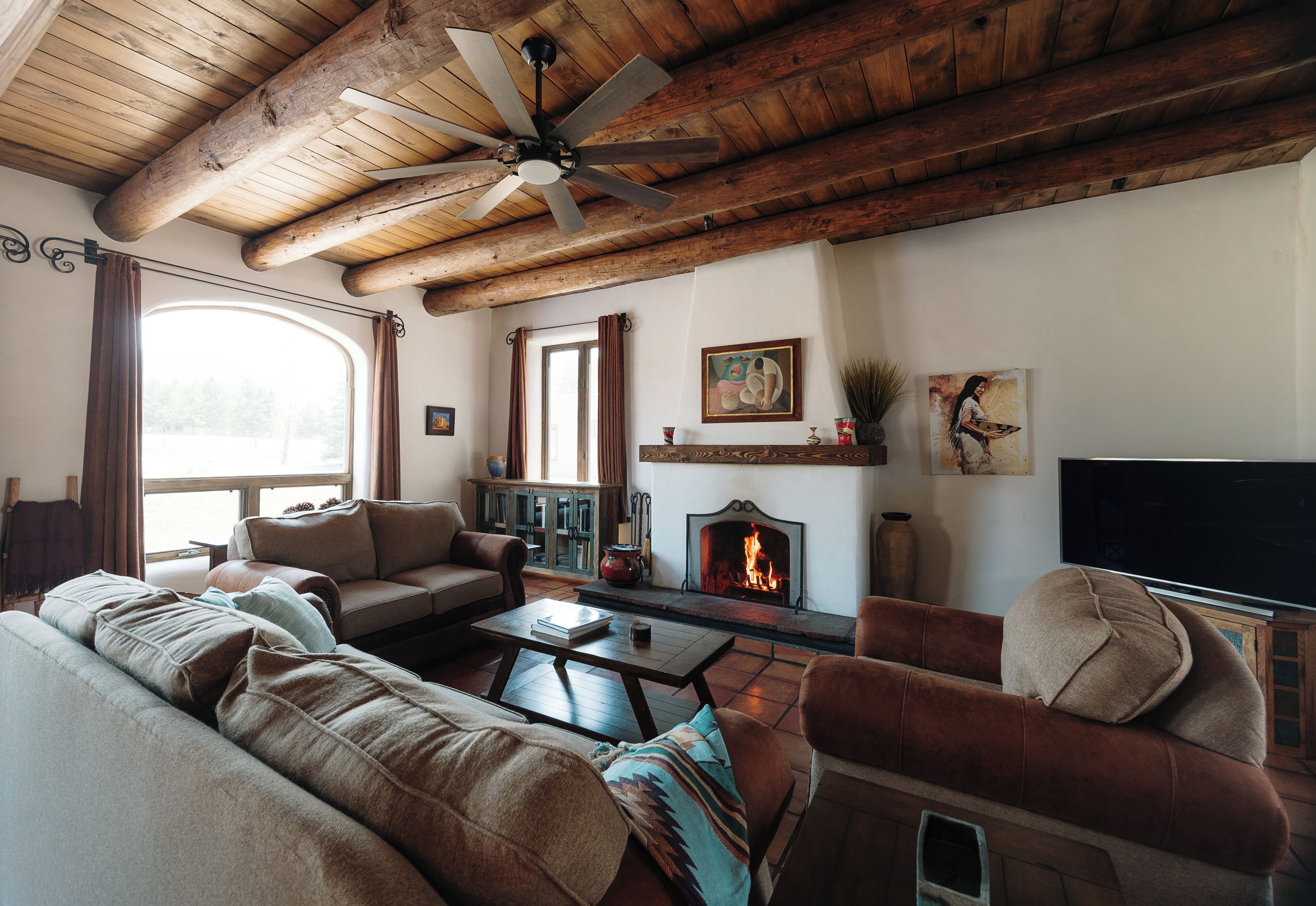 Una sala acogedora con chimenea, vigas de madera en el techo y un ventanal grande.