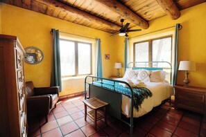 Una habitación con una cama, techo de madera y una ventana.