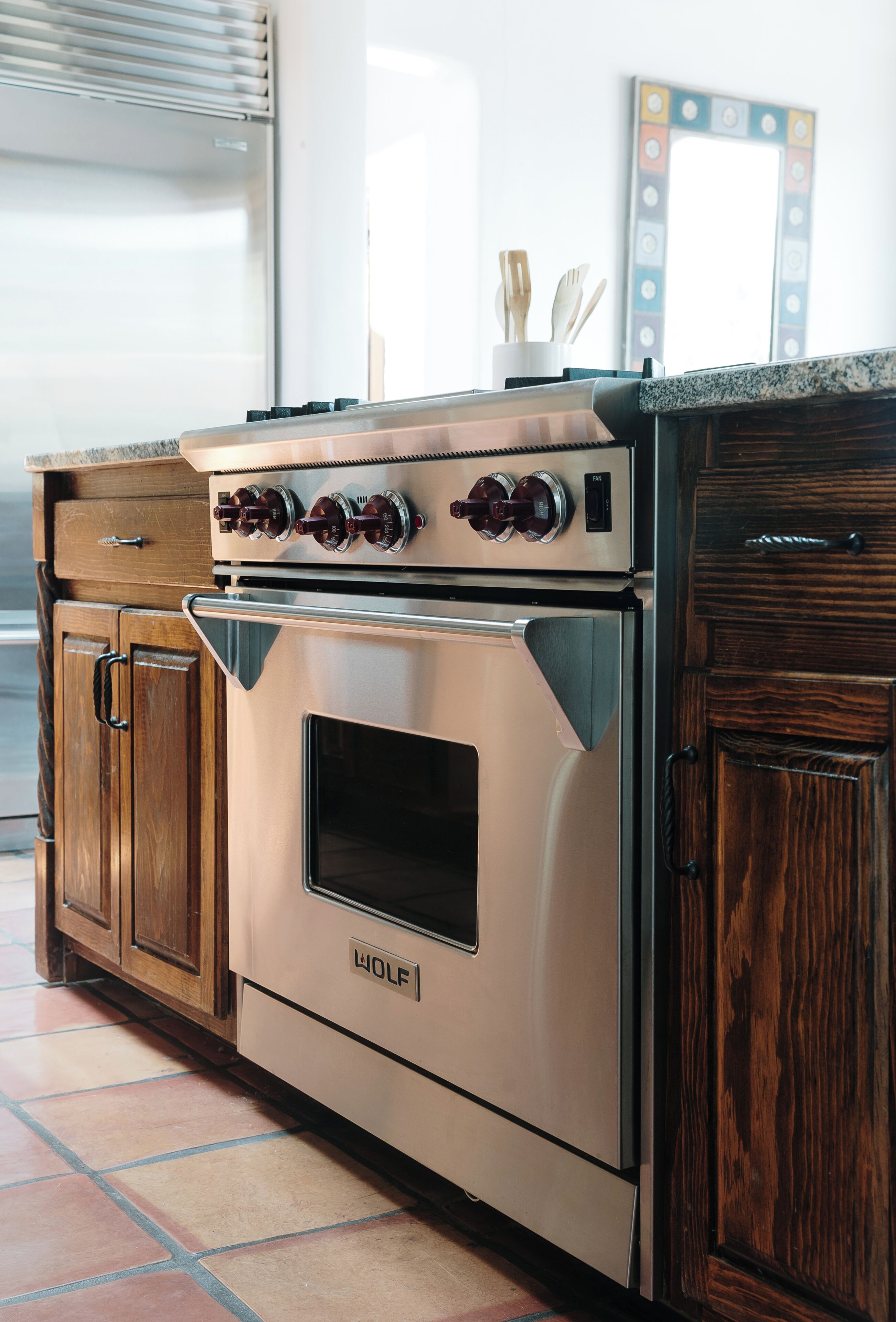 Una cocina con horno Wolf, armarios de madera y suelo de baldosas.