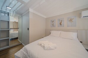 A neatly made bed with white linens and towels, a bedside table, and a wall with three framed floral artworks. - Garten - Studios mordenos (Joinville)