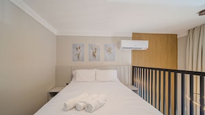 A hotel room with a bed, a nightstand, and a wall-mounted air conditioner. - Garten - Studios mordenos (Joinville)