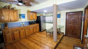 A kitchen with wooden cabinets, a refrigerator, a ceiling fan, and a rope cat tree. - Papaya Place Divers Inn, a comfortable quite place fabulous West Bay. (West Bay)