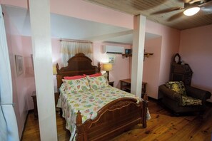 A bedroom with a wooden bed, a chair, and a small table. - Papaya Place Divers Inn, a comfortable quite place fabulous West Bay. (West Bay)