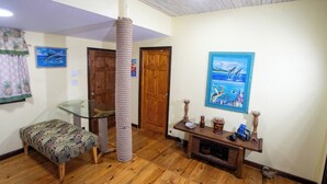 A room with a glass table, a cat tree, a wooden bench, and a wooden console table with decorative items. - Papaya Place Divers Inn, a comfortable quite place fabulous West Bay. (West Bay)