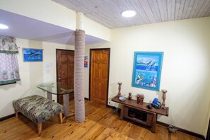 Ein Zimmer mit einem Glastisch, einer Katzenliege, einer hölzernen Bank und einer Holztruhe mit Dekorationselementen.