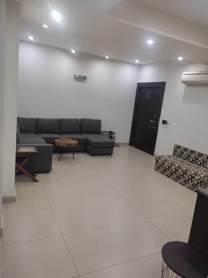 A modern living room with a sectional sofa, a patterned sofa, a small table, and a door. - 2-bedroom with 2 attached bathrooms apartment in tranquil and gated community (Rawalpindi)
