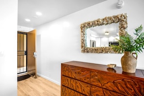 The entry sets a welcoming tone with warm wood tones, a mirror, and natural light from the interior - Valley Isle Villas | Oceanfront Studio | Car Incl. w/ 6+ Nights | VIR-107 by KBM (Lahaina)