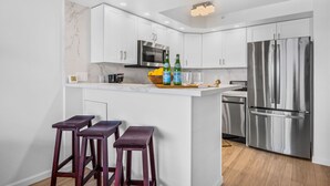 Una cocina moderna con armarios blancos, electrodomésticos de acero inoxidable y una salpicadera de mármol.