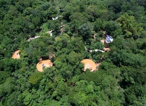 Un área boscosa con tres estructuras circulares, posiblemente cabañas, rodeadas de árboles densos.