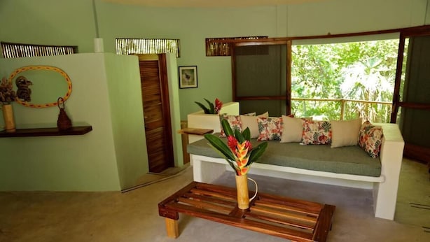 Una sala de estar con un sofá, una mesa de centro de madera y un jarrón decorativo con flores.