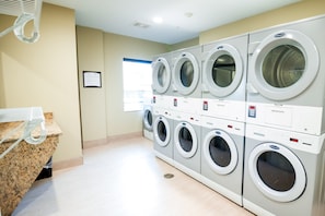 A laundry facility with multiple washing machines and a granite countertop.