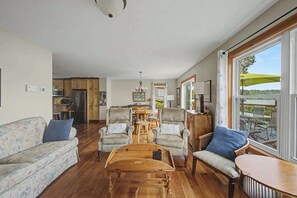 A spacious living room with a wooden coffee table, two sofas, and a dining area with a chandelier.