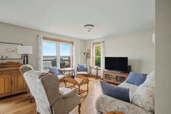 A spacious living room with a large window, a television, and a dining area.