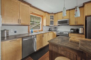 A modern kitchen with wooden cabinets, stainless steel appliances, and a central island.