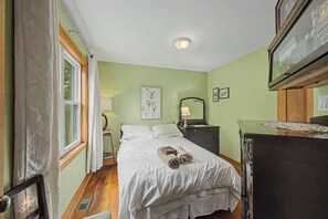 A bedroom with a bed, bedside table, lamp, and a mirror.