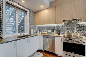 A modern kitchen with white cabinets, a stainless steel dishwasher, and a built-in oven. - Modern 2BR Condo in Prime Montreal Location (Montreal)